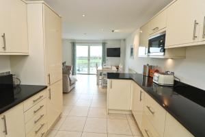 a kitchen with white cabinets and black counter tops at BY THE BEACH, The Quies, Beach House in St Merryn