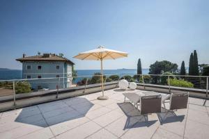 a patio with an umbrella and a table and chairs at Madeleine in Toscolano Maderno