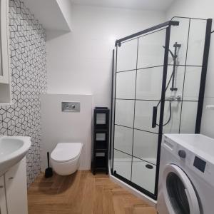 a bathroom with a toilet and a washing machine at Figaro Apartaments in Gdynia