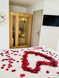 a pile of red rose petals on a bed at Vite, au bien-être in Vitteaux