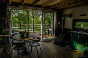 cocina con mesa y sillas y balcón en Strazdu Ligzda Off grid treehouse, en Meņģele