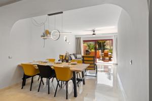 une salle à manger avec une table et des chaises jaunes dans l'établissement Beautifull penthouse, BIG solarium with seaview and exotic oasis gardens, à Estepona