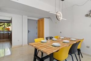 une salle à manger avec une table en bois et des chaises jaunes dans l'établissement Beautifull penthouse, BIG solarium with seaview and exotic oasis gardens, à Estepona