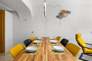 une salle à manger avec une grande table en bois et des chaises jaunes dans l'établissement Beautifull penthouse, BIG solarium with seaview and exotic oasis gardens, à Estepona
