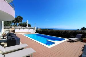 a swimming pool sitting on a deck next to a house at SUN apartment with SEA VIEW and shared POOL in Split