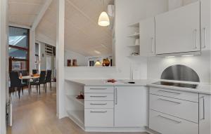 a kitchen with white cabinets and a dining room at Cozy Home In Rdby With Sauna in Kramnitse