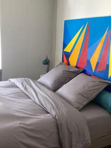 un letto con testiera colorata e cuscini sopra di King size lounge 76m2 de confort au centre ville a Mulhouse