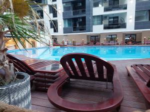 a large swimming pool with chairs and a hotel at Seaside Blues Apartment Located in 5 Star Resort in Năvodari
