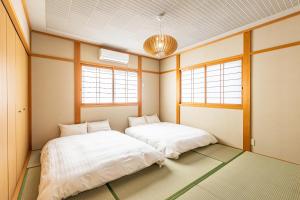 Sayuragi Villa 白浜 في شيراهاما: سريرين في غرفة بها نافذتين