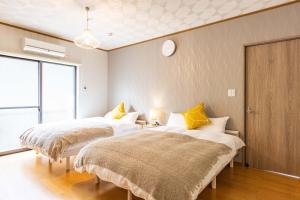 two beds in a room with a clock on the wall at Sayuragi Villa 白浜 in Shirahama