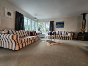 a living room with two couches and a table at La Petite Ferme Manor Kerikeri in Kerikeri