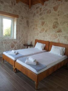 two beds in a room with a stone wall at Olive Trees in Tragaki