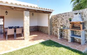 un patio con una pared de piedra, una mesa y una parrilla en Stunning Home In Chiclana De La Fronter With 2 Bedrooms, en Chiclana de la Frontera