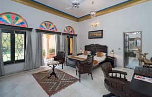 a bedroom with a bed and a table and chairs at Hotel Narain Niwas Palace in Jaipur