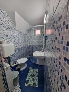 a blue tiled bathroom with a toilet and a sink at Pensiunea Soare si Luna in Praid