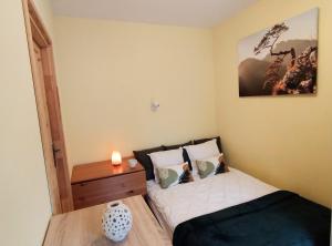 a small bedroom with a bed and a night stand at Yellow Apartment in Wieliczka