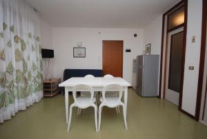 リニャーノ・サッビアドーロにあるResidenza Gardeniaの冷蔵庫付きの客室で、白いテーブルと椅子が備わります。