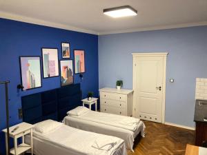1 dormitorio con 2 camas y pared azul en Hoza 35 A-E by Homeprime, en Varsovia