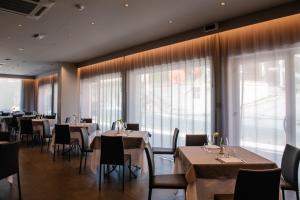 un ristorante con tavoli, sedie e ampie finestre di Hotel Principe d'Aragona a Modica