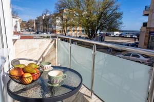 a table with a bowl of fruit and cups on a balcony at Guest rooms and apartments Desi in Balchik