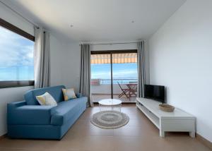 a living room with a blue couch and a tv at Turquesa & Ambar Apartments Formentera in La Savina