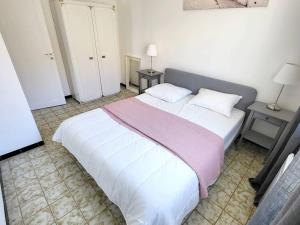 een slaapkamer met een groot wit bed en 2 tafels bij Appartement Six-Fours-les-Plages, 3 pièces, 5 personnes - FR-1-316-316 in Six-Fours-les-Plages