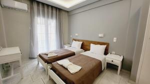 une chambre avec deux lits et un bureau et une fenêtre dans l'établissement Corfu Paloma Apartments, à Ýpsos
