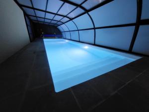 a swimming pool in a tunnel with blue lighting at Maison Victoria - avec piscine in Plédèliac