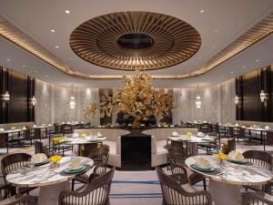 Sofitel Xiong An في Baoding: غرفة طعام بها طاولات وكراسي وثريا