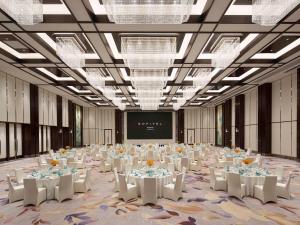 une grande salle de banquet avec des tables et des chaises blanches dans l'établissement Sofitel Xiong An, à Baoding