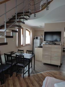 uma cozinha e sala de jantar com uma mesa e uma televisão em Tiborc Apartman em Gyula