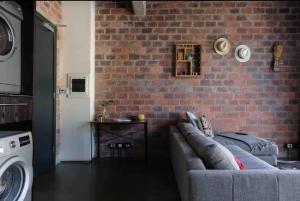 a living room with a couch against a brick wall at Industrial 1 bedroom apartment in the City Bowl in Cape Town
