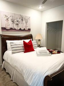 een slaapkamer met een groot wit bed met rode kussens bij Upscale Condo Full Kitchen Balcony Rooftop Pool in Jacksonville