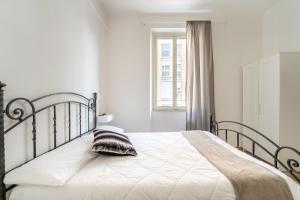 a bedroom with a bed with white sheets and a window at Rooms Piramide in Rome