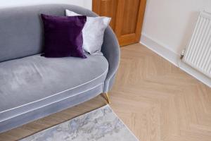 een grijze stoel met een paars kussen op een houten vloer bij JOIVY Attractive flat near Haymarket Station in Edinburgh