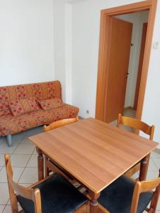 drewniany stół i krzesła w salonie z kanapą w obiekcie Appartamenti Carlotta w Rimini