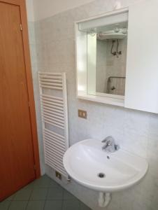 W łazience znajduje się biała umywalka i lustro. w obiekcie Appartamenti Carlotta w Rimini