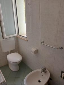 łazienka z toaletą, umywalką i oknem w obiekcie Appartamenti Carlotta w Rimini