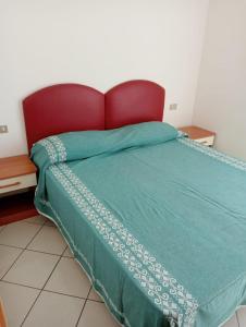 1 cama con edredón verde y cabecero rojo en Appartamenti Carlotta en Rímini