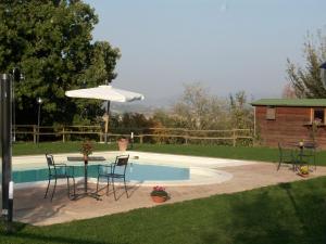 uma mesa com cadeiras e um guarda-sol ao lado de uma piscina em Girasole - Agriturismo Fogliani em Giano dellʼUmbria