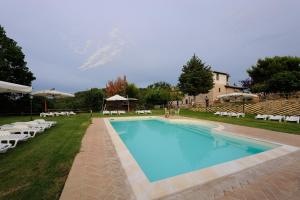 - une piscine dans une cour avec des chaises et un bâtiment dans l'établissement Rosa - Agriturismo Fogliani, à Giano dellʼUmbria