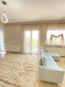 a living room with a white couch and a large rug at Olymp Family Apartments Katerini in Katerini