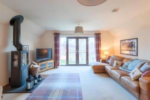 un soggiorno con divano e TV di Carn Mhor Lodge ad Aviemore