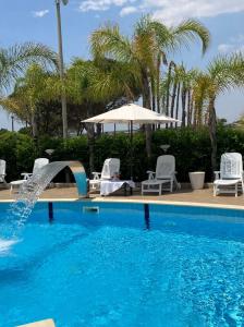 a swimming pool with chairs and an umbrella at Residence Fronte Mare in Santa Maria Del Focallo