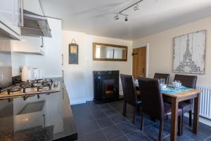 a kitchen and dining room with a table and a fireplace at Mabel Cottage in Torquay