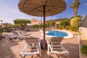 un patio con sillas, una sombrilla y una piscina en Villa moderna con piscina, en El Campello