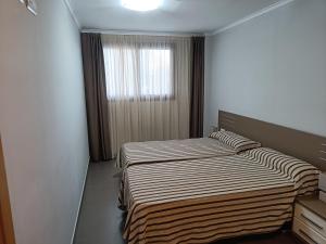 two beds in a hotel room with a window at Aparthotel El Faro in Cullera