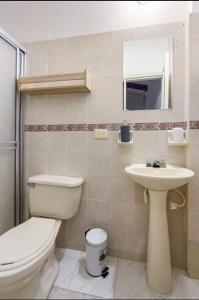 a bathroom with a toilet and a sink at La Arboleda del Rio. in Cali