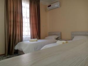 een hotelkamer met 3 bedden en een raam bij Istirohat guest house in Samarkand
