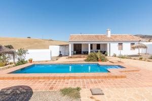 a swimming pool in front of a house at Cortijo Las Caballerias in Alora
